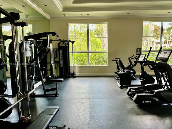 Interior view of a gym area with exercise machines and large windows.