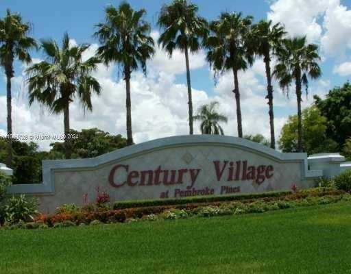 Signage for Century Village at Pembroke Pines with palm trees in the background.