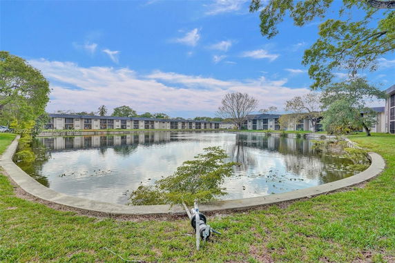 Outdoor view featuring a tranquil water body adjacent to a series of residential buildings.
