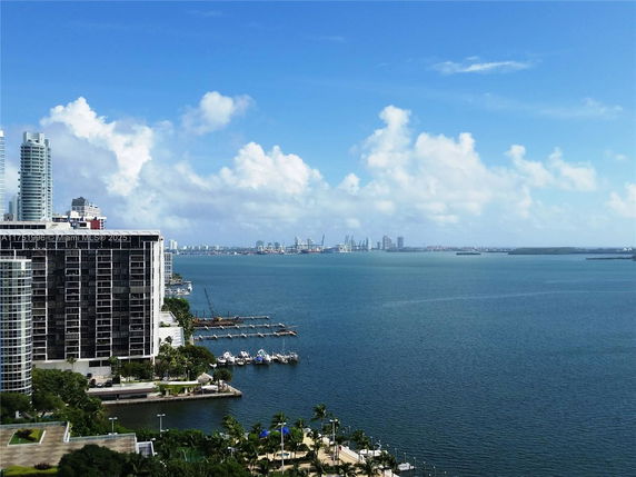 Panoramic view of buildings and bay with boats and city skyline in the distance.