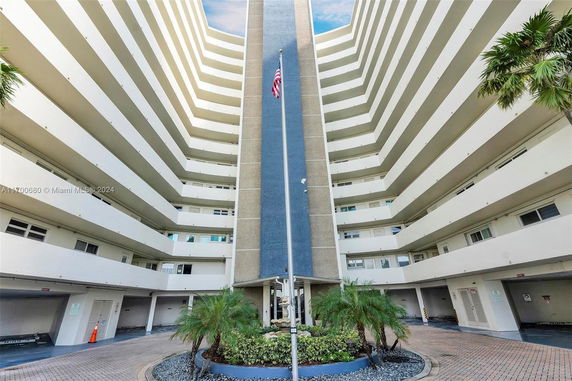 Front view of a multi-story building with balconies and a central flagpole.
