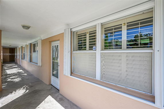 Exterior view of a building corridor with doors and windows.