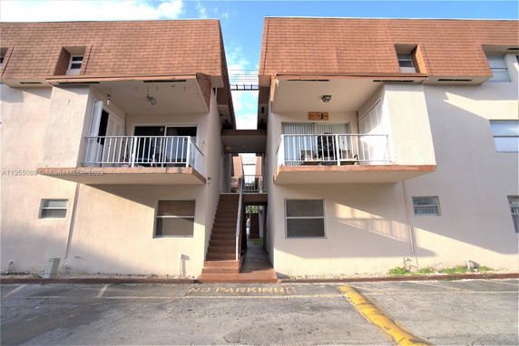 Front view of a building with balconies and stairs leading up to the second floor.