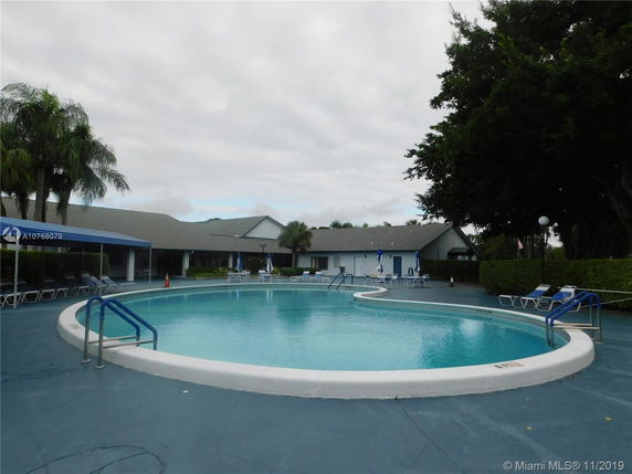 Outdoor swimming pool area with surrounding chairs and umbrellas.
