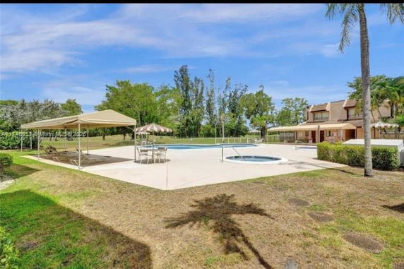 Outdoor area with a swimming pool and surrounding greenery beside a building.