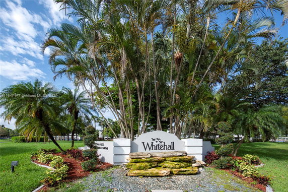 Entrance sign for Whitehall surrounded by palm trees and greenery.