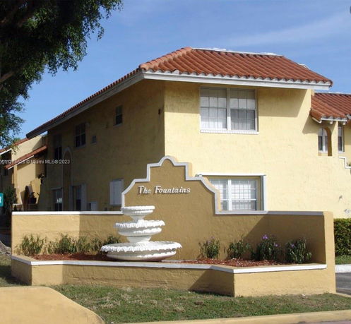 Front view of a two-story building with a decorative fountain and sign.