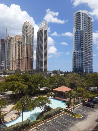 View of tall modern skyscrapers with a small gazebo and pool in the foreground.