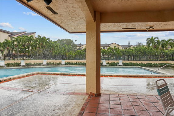 View of a swimming pool with lounge chairs and surrounding palm trees.