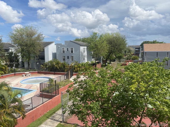 Outdoor view of a fenced swimming pool area surrounded by residential buildings.