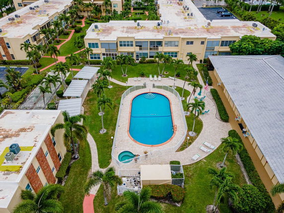Aerial view of an outdoor swimming pool surrounded by buildings and landscaped paths.