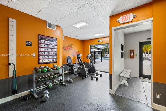 Indoor gym area with exercise bikes, dumbbells, and fitness posters.