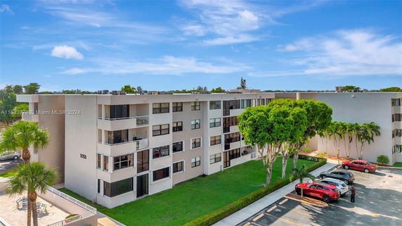 Front view of a multi-story apartment building with parking area.
