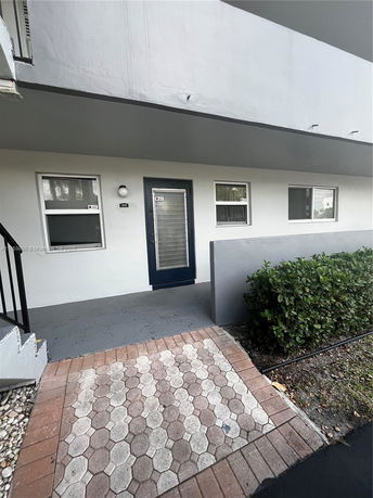 Front view of a building entrance with a paved walkway and a small porch area.