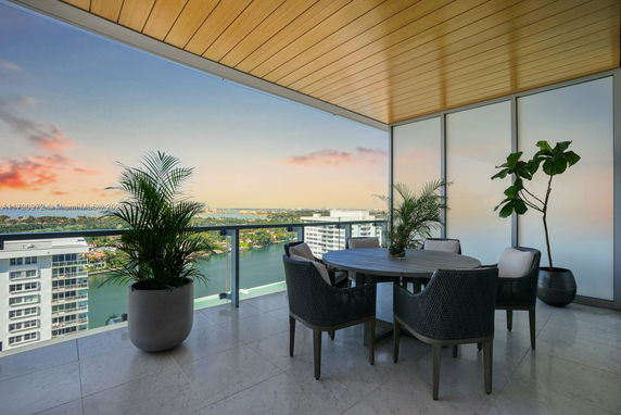 Panoramic view from a balcony with a dining area overlooking cityscape and water.