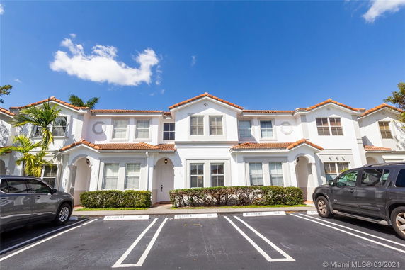 Front view of a two-story townhouse with a tiled roof and white exterior.