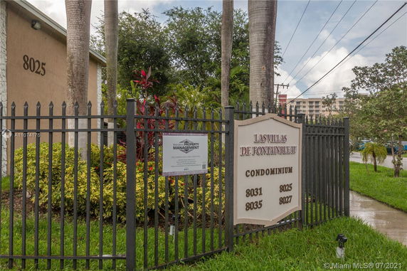 Front view of a condominium building with a gated entrance and signage.