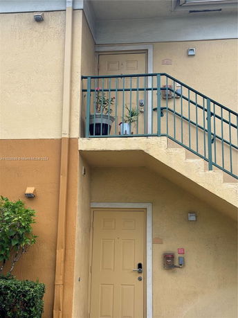 Front view of a two-story building with an external staircase leading to the upper floor.