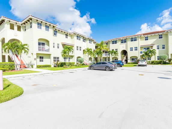Front view of a multi-story apartment building with a parking area in front.