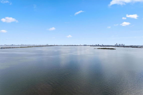 Panoramic view of a body of water with distant city skyline under a clear sky.