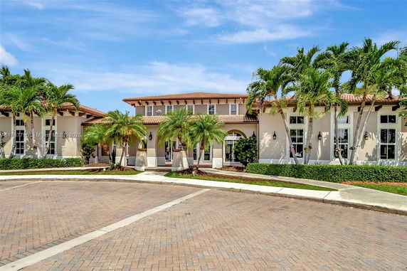 Front view of a large house with palm trees and a tiled roof.