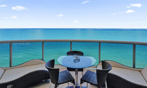 Balcony with ocean view and outdoor seating arrangement.