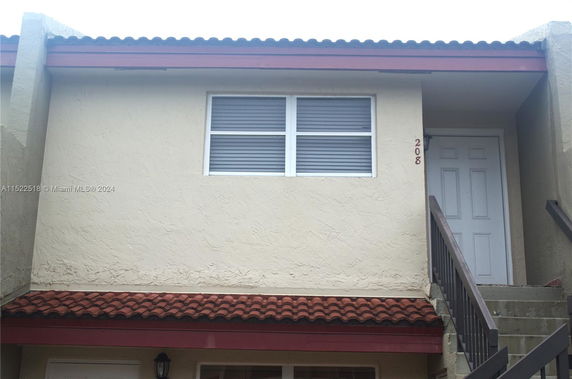 Front view of a two-story building with stairs leading to a second-floor door.