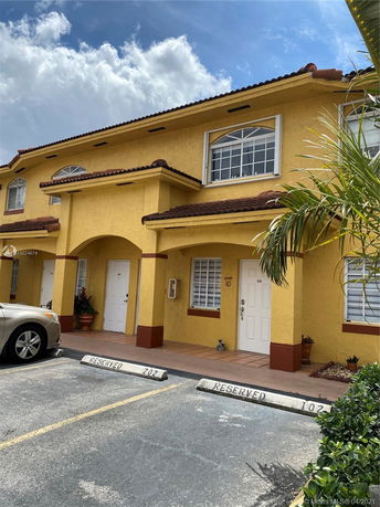 Front view of a two-story house with yellow exterior and arched windows.