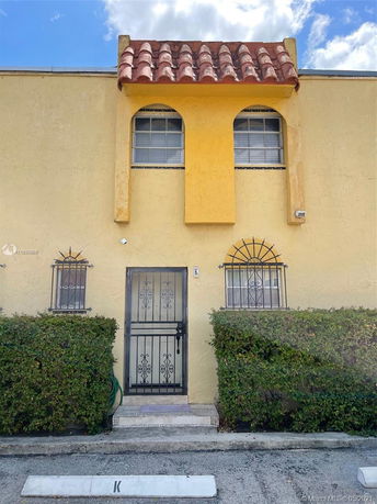 Front view of a two-story building with decorative iron door and arched windows.
