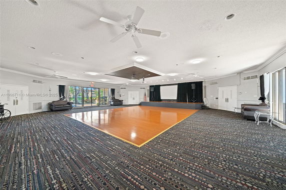 Spacious room with a stage area and seating, suitable for recreational activities.