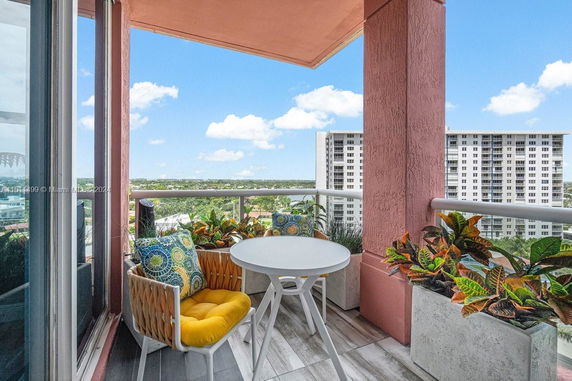 Balcony view with a table and chairs overlooking city buildings and greenery.