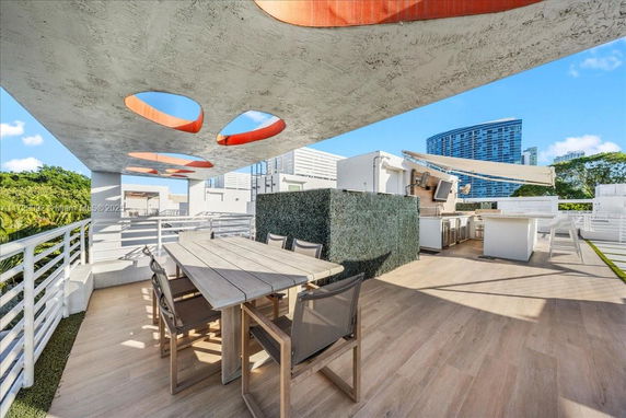 Rooftop area with dining table, chairs, and outdoor kitchen setup.