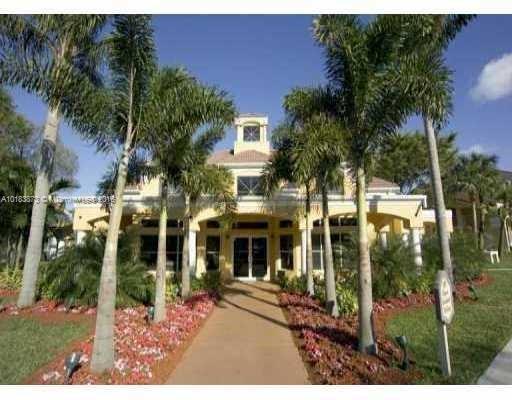 Front view of a multi-story house with a prominent entrance and palm trees.