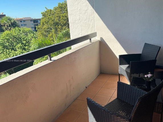 View from a balcony with outdoor seating and surrounding trees.