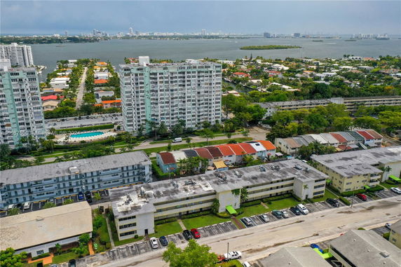 Aerial view of residential buildings with a cityscape and water body in the background.