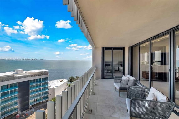 Balcony view overlooking ocean and nearby building.