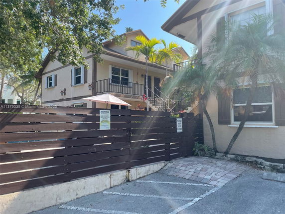 Front view of a two-story house with a wooden fence and exterior stairs.