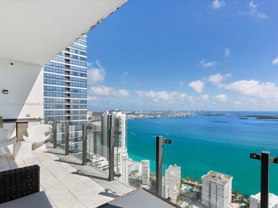 Panoramic view of the city and ocean from a high-rise balcony.