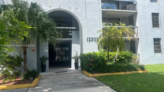 Front view of a multi-story building with balconies and an arched entrance way.