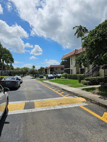 Street view of a residential area with multi-story buildings and parked cars.