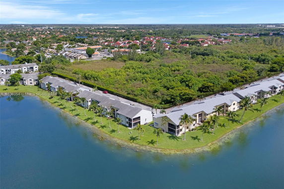Aerial view of residential buildings surrounded by greenery and a lake.