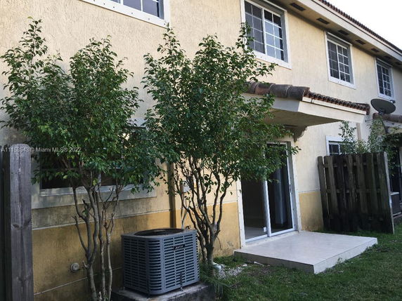 Front view of a two-story house with large windows and a sliding glass door.