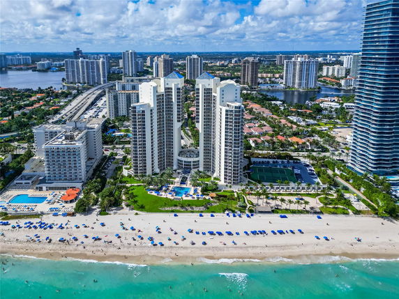 Aerial view of beachfront high-rise buildings with surrounding urban landscape.
