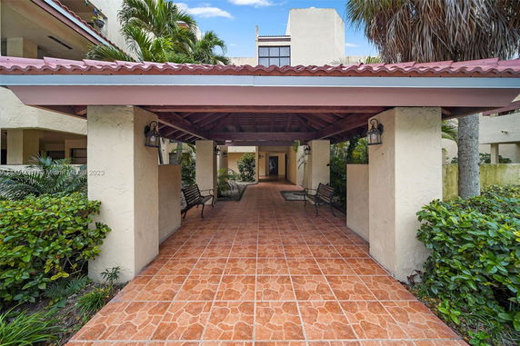 Covered outdoor entrance with tiled walkway and seating area.