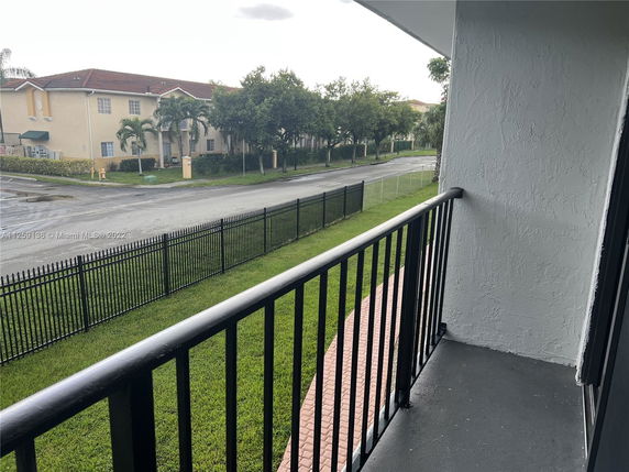 View from balcony showing a street and nearby buildings with lawns.