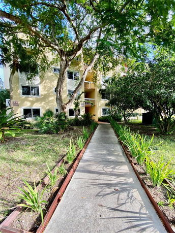 Front view of a multi-story building with trees and pathway leading to the entrance.
