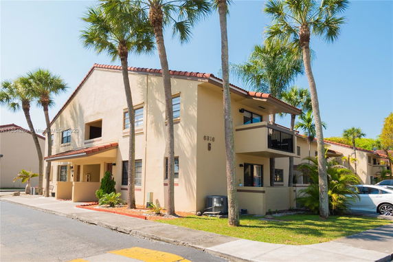 Front view of a two-story house with palm trees.