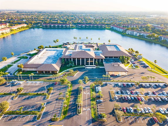 Aerial view of a large complex with multiple buildings surrounded by a parking lot and located adjacent to a body of water.