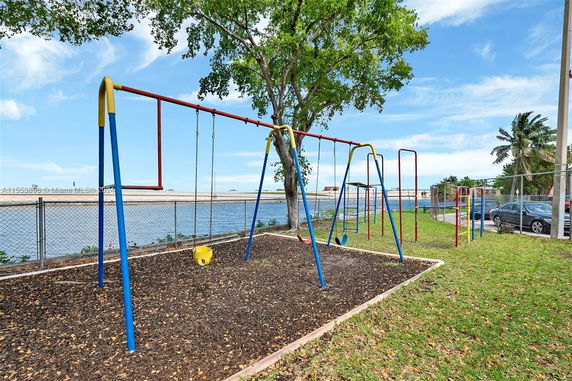 Playground with swings and play equipment near a lake.