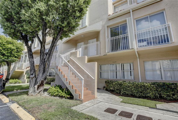 Front view of a multi-story residential building with stairs leading to the entrance.